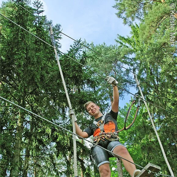 Junge klettert glücklich im Kletterwald Pottenstein