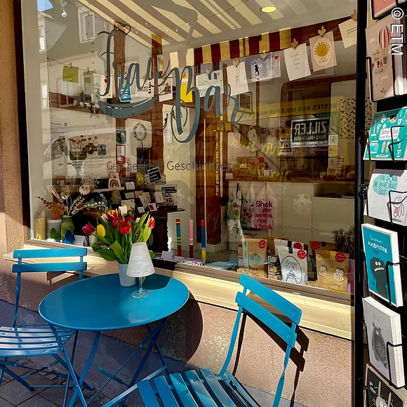 Frau Bär. Geschenke & Geschichten Geschäft Frau Bär von außen, Schaufenster,
zwei Stühle und Tisch davor