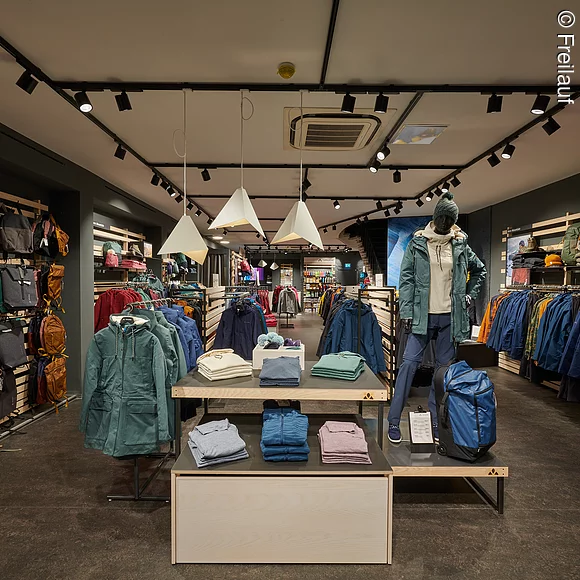 Verkaufsraum innen, Outdoorjacken in verschiedenen Farben, Shirts, Rucksäcke