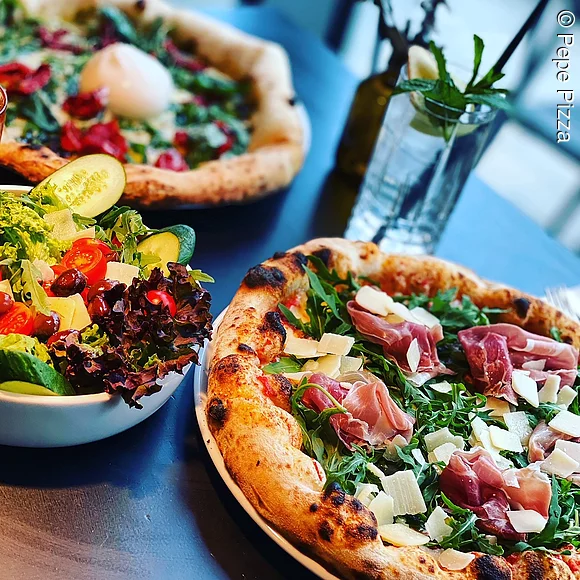 zwei Pizzen, angeschnitten, Salat