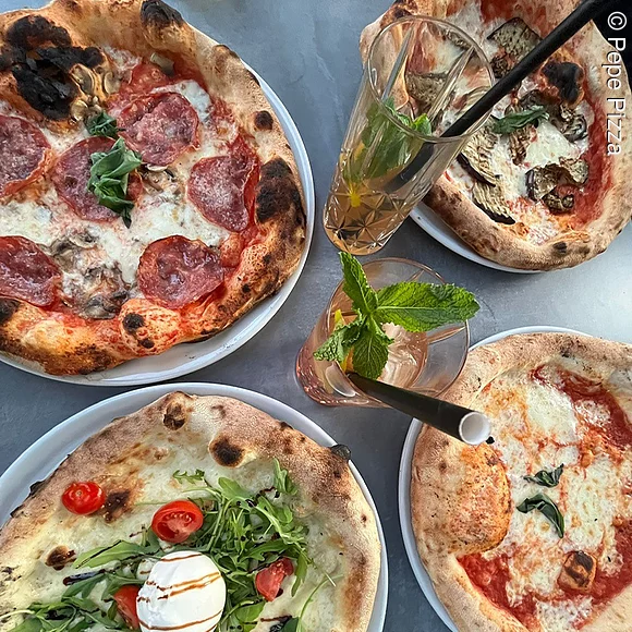 Vier unterschiedliche Pizzen auf Tellern