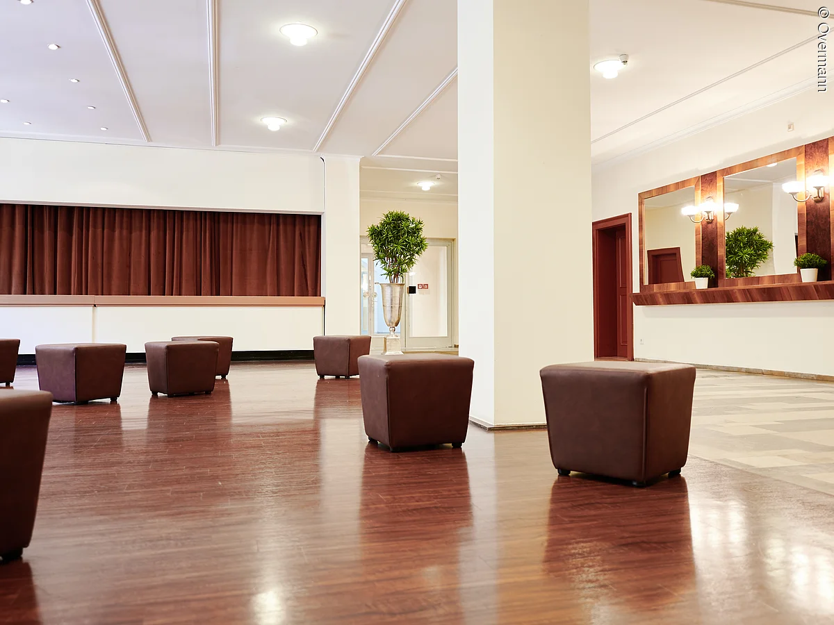 Foyer im Erdgeschoss des Redoutensaals mit Sesseln und Blick auf Garderobe