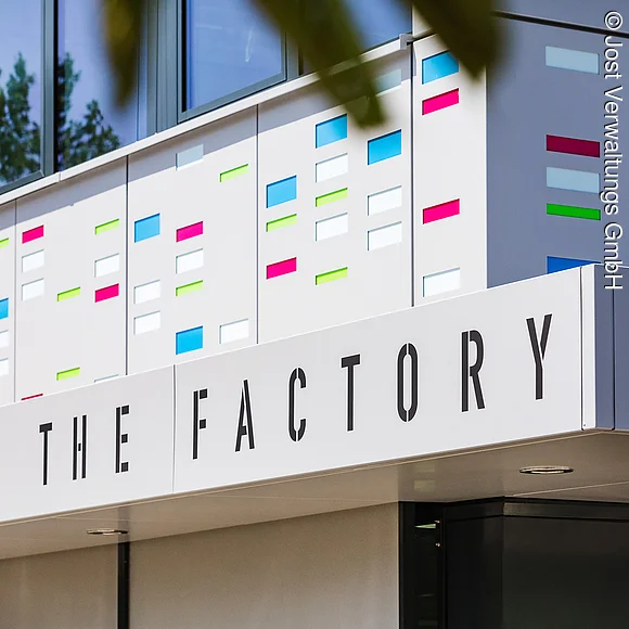 Außenansicht des Eingangs mit Schriftzug "The Factory"