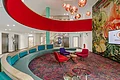 Eingangsbereich mit geschwungenem Sofa, Sesseln und bunten Bild an der Wand
