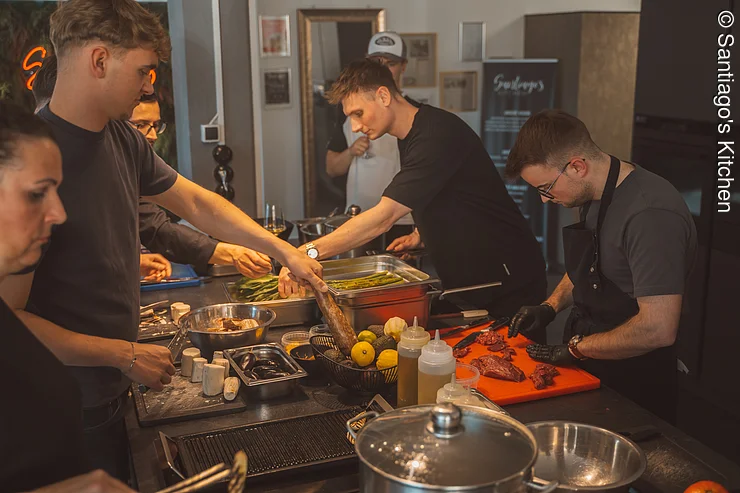 Teamkochen Fünf Personen kochen gemeinsam an einer Kochinsel