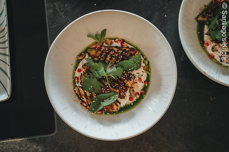 Gericht weißer Teller mir gegrilltem Fleisch, Minze, Nüssen und Granatapfelkernen