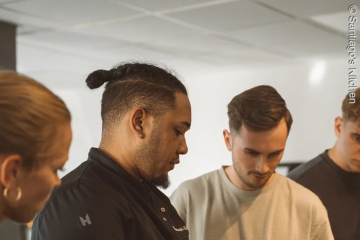 Teambuilding Kochkurs Professioneller Koch erklärt drei Personen während eines Kochkurses die richtige Schneidetechnik mit meinem Messer