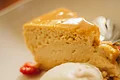 Weißer Teller mit einem Stück Kuchen, einer Kugel Eis und Obst