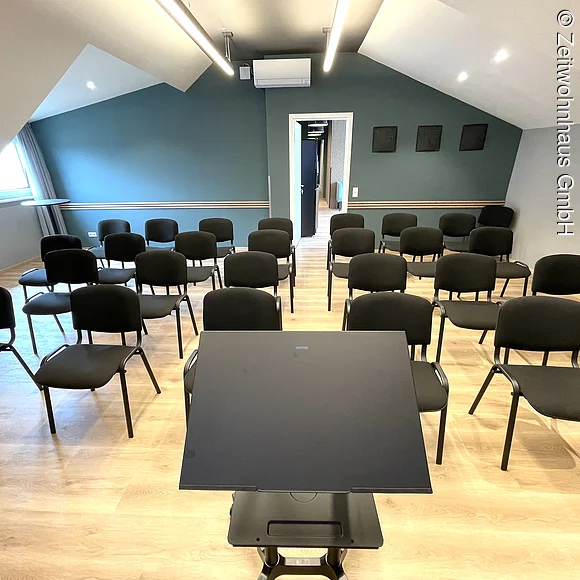 Seminarraum mit Reihenbestuhlung und Block vom Rednerpult aus