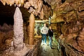 Das Bild zeigt zwei Besucher, die die Stalaktiten und Stalakmiten der Binghöhle bewundern.