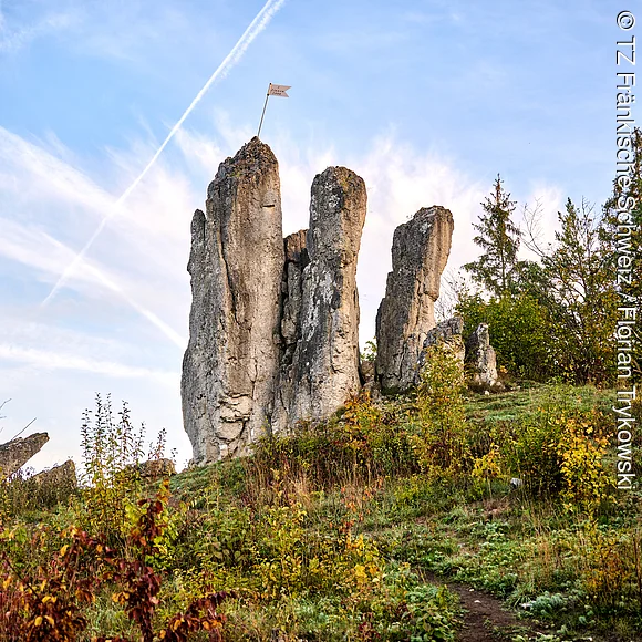 Auf einem Hügel erheben sich drei steil aufragende Felsen.