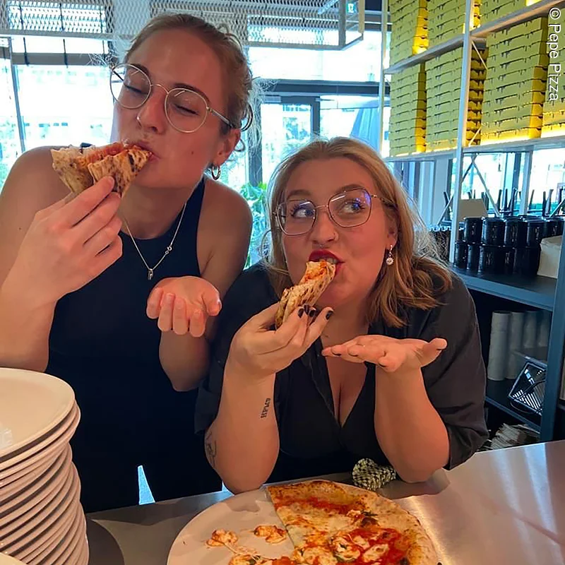 Zwei Mädels, die sich eine Pizza schmecken lassen