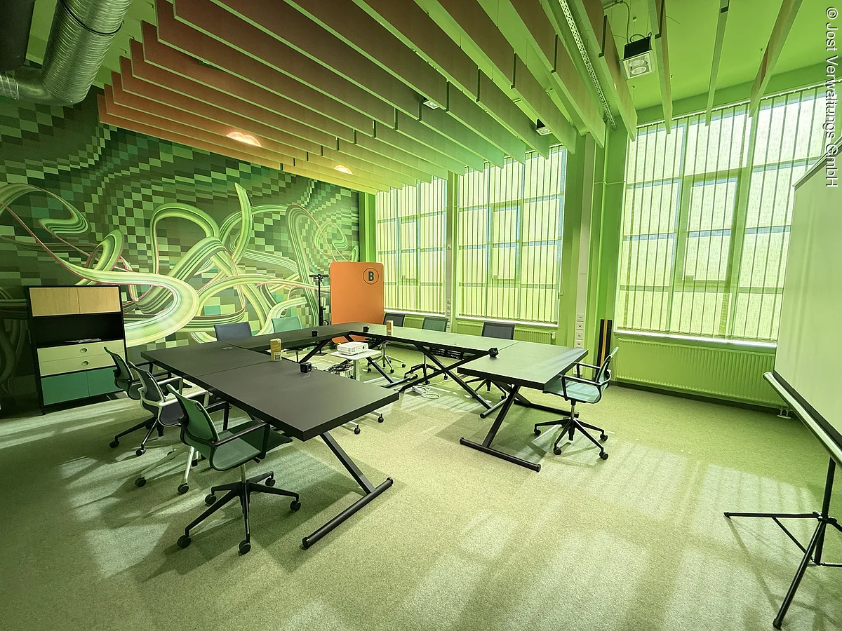 قاعة ندوات بطاولات وكراسي. عناصر خضراء على ورق الجدران وإضاءة خضراء.