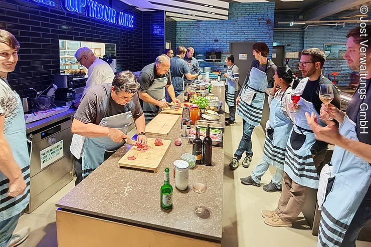Bei einem Teamevent in der Showküche kochen Menschen gemeinsam in der Küche.