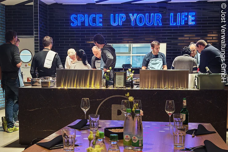 Einige Menschen stehen zusammen in der offenen Showküche und kochen als Teamevent.