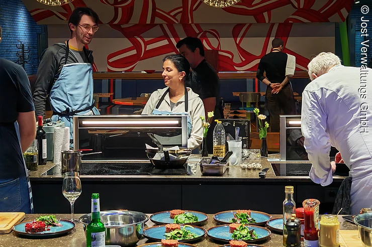 Drei Menschen kochen zusammen an den Kochfeldern in der Showküche