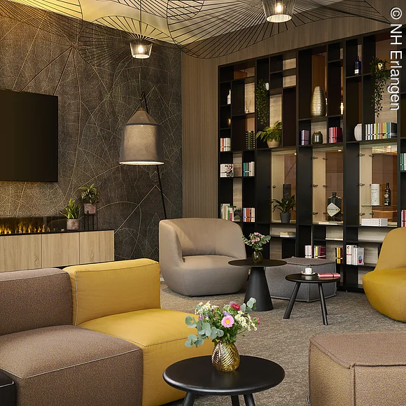 Lobby eines Hotels mit Sitzmöglichkeiten, Kamin und Bücherregal