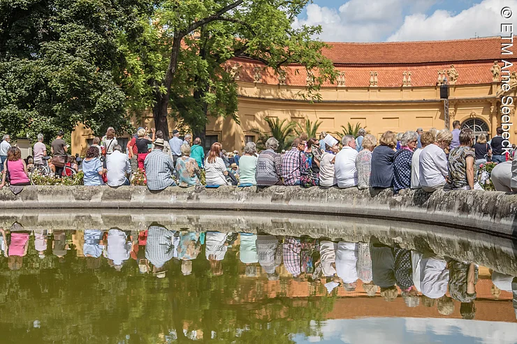 Zuhörer sitzen auf dem Hugenottenbrunnen während der Schlossgartenkonzerte