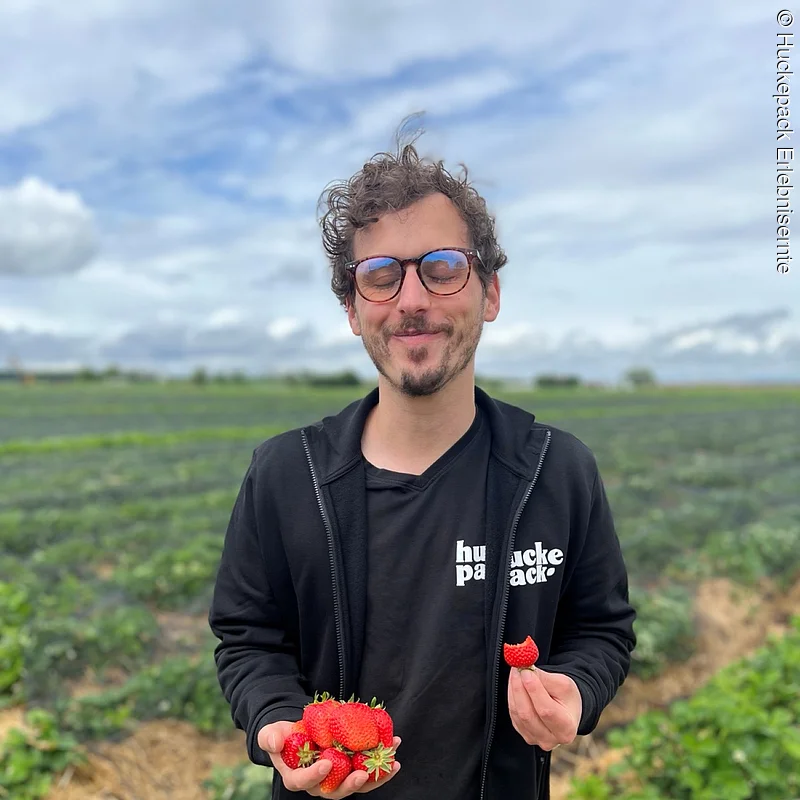 Lukas Niedermann von Huckepack Erlebnisernte Person steht mit Erdbeeren auf einem Feld